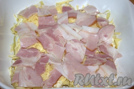 Сырокопчёный бекон нарезать на части. Поверх сыра разложить ломтики бекона. Запекать картофель с беконом и сыром в разогретой духовке 10-15 минут при температуре 180 градусов (до лёгкого зарумянивания бекона и сыра).
