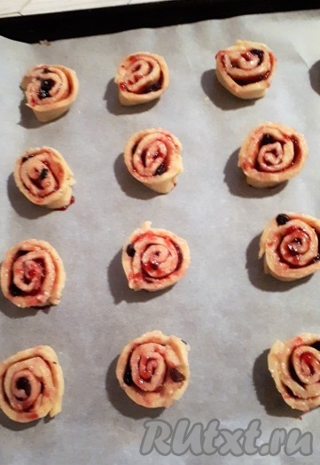 Подготовленные кусочки выложить на противень, застеленный пергаментом, срезом вверх, в виде "улиточек" на некотором расстоянии друг от друга. Аналогично сформировать "улитки" из второй части творожного теста и тоже выложить на застеленный противень.
