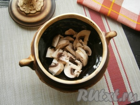 В горшочек влить растительное масло. Шампиньоны вымыть, обсушить, нарезать на 4-6 частей и половину от общего количества грибов выложить на дно горшочка, немного посолить и поперчить.
