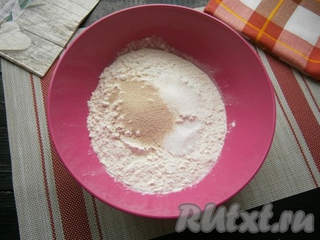 Просеять в миску муку, добавить сухие дрожжи, сахар и соль, перемешать.
