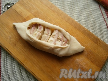 Немного пирожок придавить и сделать продольный разрез острым ножом, но не до самых краёв. Руками приоткрыть тесто, чтобы начинка из теста с ветчиной была хорошо видна. Сыр окажется внизу пирожка.
