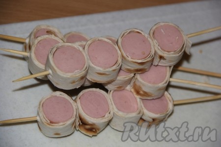 Кусочки сосисок в лаваше наколоть на шпажки (как на фото).
