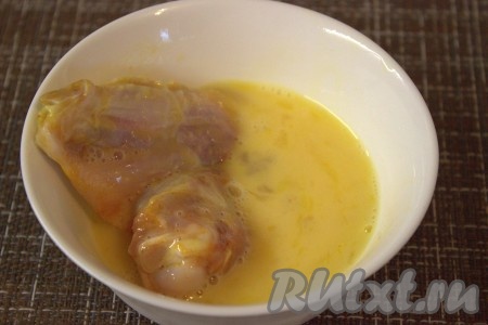 В подходящую ёмкость вбить два яйца, взбить вилкой до однородного состояния. В другую ёмкость насыпать панировочные сухари. Сначала обмакнуть куриные крылышки со всех сторон в яичную смесь.