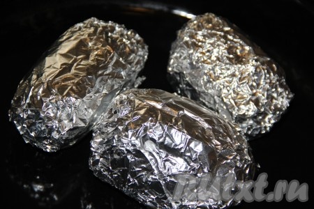 Мы будем запекать картошку в кожуре, поэтому подбирайте только хорошие клубни, без дефектов. Картофель хорошо вымыть. Каждую картошину выложить на лист фольги. Сбрызнуть картофель растительным маслом и посолить. Плотно завернуть каждую картошину в фольгу, выложить на противень и запекать в разогретой духовке при температуре 250 градусов, примерно, 55-60 минут (если картошина легко прокалывается зубочисткой, значит она готова). Время приготовления зависит от размера и сорта вашего картофеля. 
