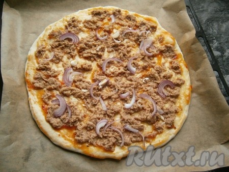 Далее на тесто выложить консервированного тунца и тонкие перья (или полуколечки) очищенного лука.
