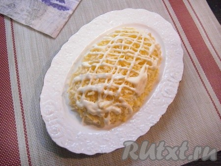 Последним слоем будет сыр твёрдых сортов, натёртый на средней (или мелкой) тёрке, нанести сеточку из майонеза.
