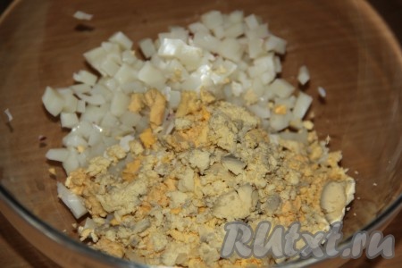 Выложить кубики кальмара в тарелку. Яйца заранее сварить (с момента закипания воды варить минут 10), остудить. Очистить яйца и отделить белки от желтков. Желтки раскрошить и добавить к кальмарам.
