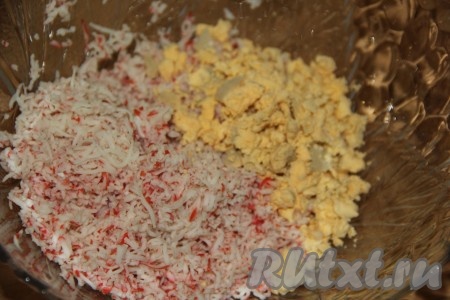 Выложить крабовую крошку в миску. Варёные яйца разделить на белки и желтки. Яичные желтки раскрошить и добавить к крабовой массе.
