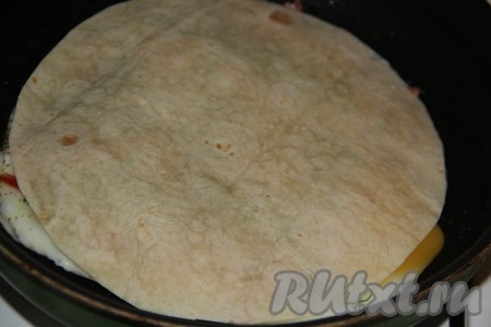 Накрыть яичницу вторым листом лаваша и слегка прижать.&nbsp;Пока мы выкладывали начинку, низ нашей лепёшки из лаваша уже приготовился.