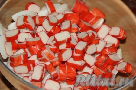 Очистить крабовые палочки от целлофановой плёнки, а затем нарезать на небольшие кусочки.
