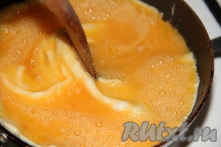 И как только яичница начнёт "схватываться", нужно с помощью лопатки аккуратно сдвигать "схватившуюся" яичную массу к середине сковороды.