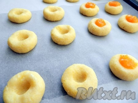 Затем каждый шарик немного придавить, сделать пальцем углубление. В каждое углубление в тесте выложить примерно по 1 чайной ложке джема.