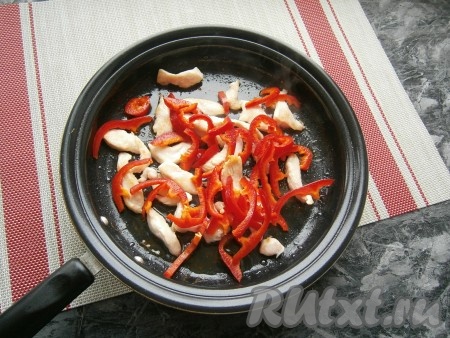 Растительное масло разогреть в сковороде, выложить кусочки куриного филе и обжарить на среднем огне, чуть подсолив мясо, до готовности и лёгкой румяности (5-7 минут), периодически перемешивая. Затем добавить в сковороду нарезанный тонкой соломкой сладкий болгарский перец.
