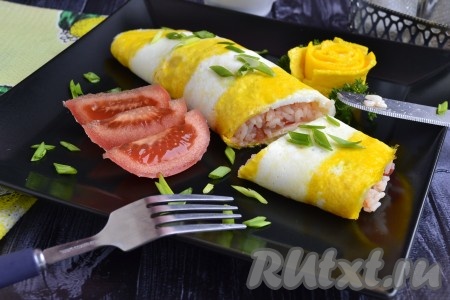 Необычайно красивый, вкусный и сытный омлет с рисом, приготовленный по-японски, переложить на красивую тарелку, посыпать его зелёным луком. Из убранных желтковых полосочек свернуть розочки и выложить рядом с омлетом. Подавать омлет со свежими овощами.