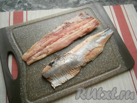 Селёдку разморозить, удалить голову, хвост, внутренности, снять шкуру, разделать рыбу на филе, удалив все крупные кости.
