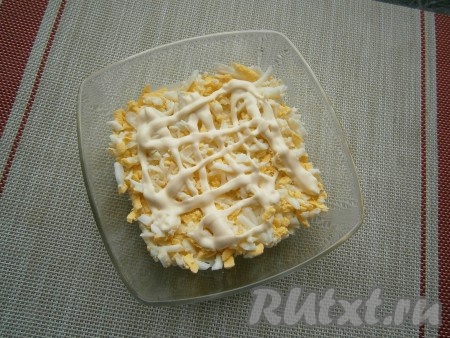 Следующим слоем выложить натёртые на крупной тёрке варёные яйца, которые тоже нужно смазать майонезом и немного посолить.
