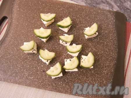 Сверху на каждом кубике разместить по половинке кружочка свежего огурца.
