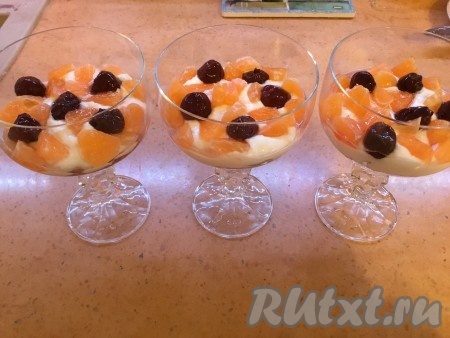 В креманки выкладываем сначала измельчённое печенье, затем - половину творожной массы. Сверху раскладываем нарезанные дольки мандаринов и вишню без косточек.