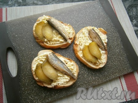 На каждый бутерброд поверх яичной массы выложить по 1-2 шпротинке и по 2 кружочка солёного огурчика.
