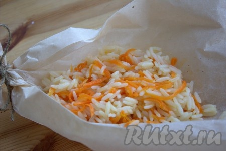 На квадратный лист пергаментной бумаги выложить 2-3 столовые ложки риса с морковью и сформировать из пергамента "лодочку", завязав ниткой концы бумаги с двух сторон.

