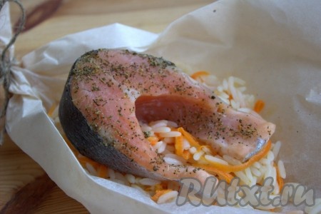 Затем поверх риса выложить 1 стейк форели. Аналогично сформировать все "лодочки" из пергамента с рисом и стейками форели.
