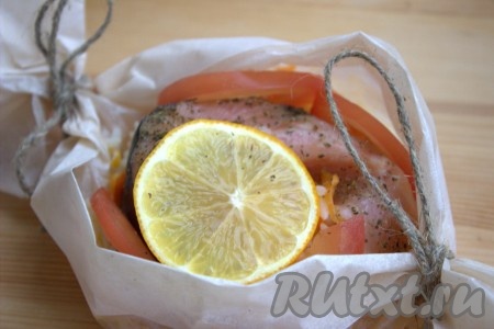 Помидор вымыть, нарезать полукружочками. Поместить в каждую "лодочку" с рисом и форелью по несколько полукружочков помидора, поверх рыбы выложить дольку лимона (как на фото). Переложить рыбу в пергаменте на противень и поставить запекаться в заранее разогретую до 200 градусов духовку на 20 минут.
