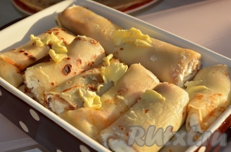 Складываем налистники с творогом в смазанную форму, сверху раскладываем кусочки сливочного масла.
