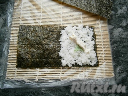 По середине риса разместить немного острой горчицы васаби и полосочку сливочного сыра.
