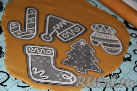 Готовое тесто разделить на 4-6 частей. С одной частью теста работаем, остальное тесто убираем в холодильник. С помощью скалки раскатать одну часть теста в пласт толщиной, примерно, 5-6 мм. Вырезать пряники, используя формочки или трафареты (можно сделать трафареты, нарисовав нужную картинку на бумаге и вырезав). Я прикладываю к раскатанному тесту трафареты и вырезаю пряники ножом (можно воспользоваться формочками).
