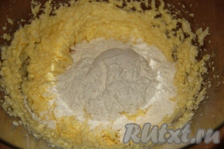 Добавить погашенную соду, начать понемногу добавлять муку, каждый раз хорошо вмешивая её. Вначале перемешивать тесто столовой ложкой, а как только тесто начнёт собираться в ком, продолжать замешивать его руками.