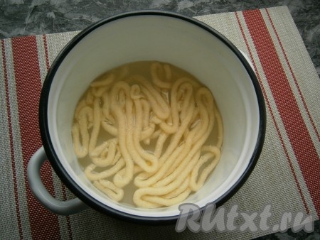 В кастрюлю налить около 1 литра воды, поставить на огонь. Вскипятить воду, всыпать немного соли. В кондитерском мешке обрезать кончик и выдавливать тесто в кипящую воду в виде лапши. Варить домашнюю яичную лапшу нужно в 2 этапа (то есть выдавить только половину жидкого теста из кондитерского мешка), чтобы лапшичка не слиплась при варке.