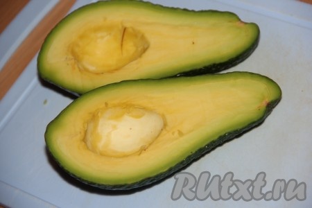 Авокадо разрезать пополам и удалить косточку. Кожуру с авокадо мы не снимаем, она будет придавать форму нашим лодочкам. Для рецепта выбирайте достаточно мягкие, спелые плоды, с них кожура будет отделяться хорошо, так что при подаче в лодочках можно будет без труда самостоятельно снять кожуру и скушать авокадо. С неспелых плодов кожура отделяется тяжело.
