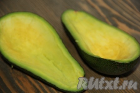 С помощью столовой ложки удалить часть мякоти из авокадо, сформировав лодочки (именно в сформированные лодочки из авокадо в дальнейшем и будет выкладываться салат с креветками).
