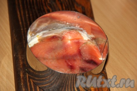 Красную рыбу нарезать на тонкие ломтики. Выложить слой красной рыбы.
