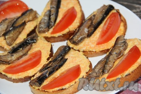 Помидор вымыть, обсушить, нарезать на дольки. Рядом со шпротами выложить на каждый бутерброд по дольке помидора.