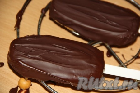 Вставить палочки в эскимо и покрыть пирожное растопленным шоколадом. Так как пирожное холодное, шоколад быстро схватывается. Оставить пирожные на столе или убрать в холодильник на 15 минут, чтобы шоколад полностью застыл.
