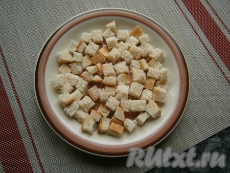 Выложить кубики хлеба в подходящую для микроволновки тарелку в один слой, чуть посолить их.