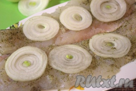 Очистить и нарезать колечками репчатый лук. На каждое филе хека выложить по несколько колечек лука и отставить на 15-20 минут в сторонку.
