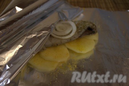 Картошку с филе хека накрыть сверху фольгой, а затем плотно завернуть со всех сторон, формируя как бы "конверт". Аналогично завернуть в фольгу оставшийся картофель с филе рыбы.
