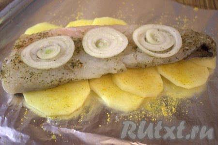 Поверх картофеля выложить одно филе хека с луком.
