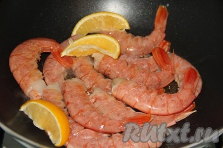 Добавить пару долек лимона и выдавить сок из 1/2 лимона. Жарить лангустинов на сильном огне в течение 2-3 минут, периодически перемешивая.