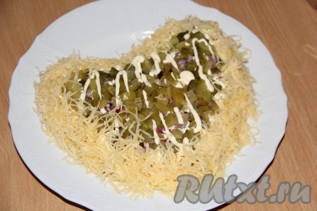 Нанести сетку из майонеза поверх огурцов и на бока салата. Сыр натереть на мелкой тёрке и выложить высокий бортик салата (как на фото).