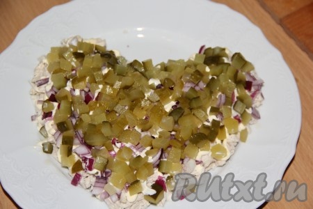 Огурцы нарезать на мелкие кубики и аккуратно выложить поверх лука.
