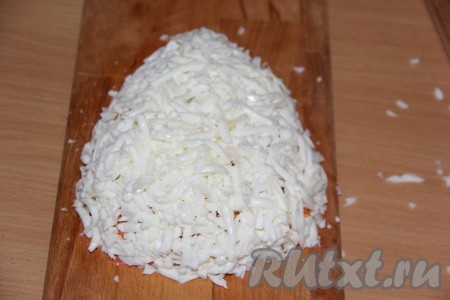 Предварительно сварить вкрутую 3 яйца (варить нужно минут 10), остудить. Затем очистить яйца и разделить на белки и желтки. Натереть белки на тёрке и покрыть ими салат.
