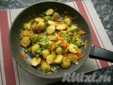 Перемешать, накрыть сковороду крышкой и тушить брюссельскую капусту с овощами на небольшом огне в течение минут 15. Затем добавить измельчённую зелень петрушки и мелко нарезанный чеснок, перемешать, потушить блюдо ещё 2 минуты и выключить газ.
