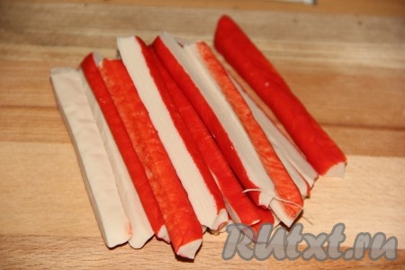 Разморозить крабовые палочки при комнатной температуре, а затем разрезать пополам.
