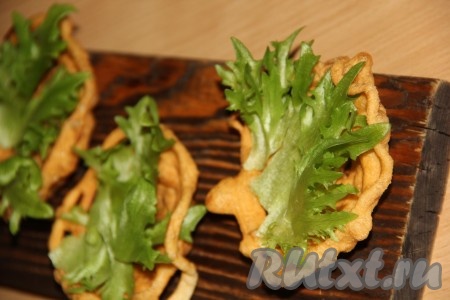 Корзинки полностью остудить. В каждую остывшую корзиночку положить лист зелёного салата, а на него выложить пару столовых ложек салата с красной рыбой и огурцом.
