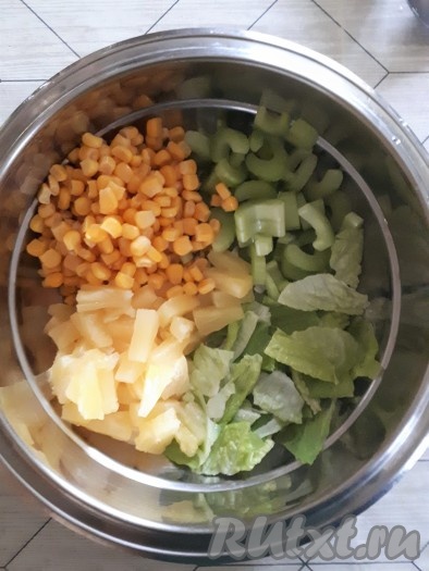 Листовой салат вымыть, обсушить, порвать руками листья на небольшие кусочки, выложить в миску. Черешковый сельдерей нарезать тоненькими пластинками и добавить к листьям салата. Сюда же выложить консервированную кукурузу и ананасы (если ананасы в кольцах - нарезать на небольшие кусочки).