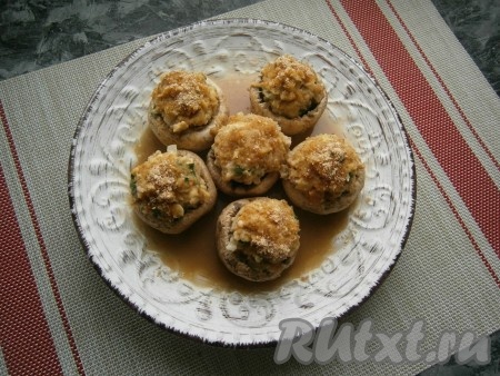 Отправить фаршированные шампиньоны в микроволновку на 8 минут при мощности 750 Ватт. За это время закуска будет полностью готова, грибы выделят достаточно много жидкости, которую нужно слить.
