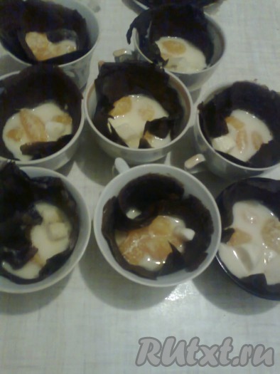 Разъёмную (или не разъёмную форму) застилаем пищевой плёнкой так, чтобы края свисали (свисающие края помогут в дальнейшем извлечь торт из формы). Два блина оставляем для низа и верха торта.
Остальные 8 блинов выкладываем по одному в 8 чашек (или любую подходящую посуду). В каждую чашку поверх блина кладём восьмую часть от всех нарезанных фруктов и заливаем йогуртом с желатином. Часть йогурта с желатином оставляем для заливки верха торта.